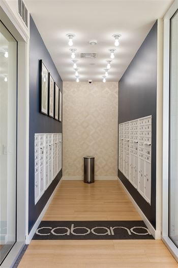A hallway with a black and white carpet and a trash can.